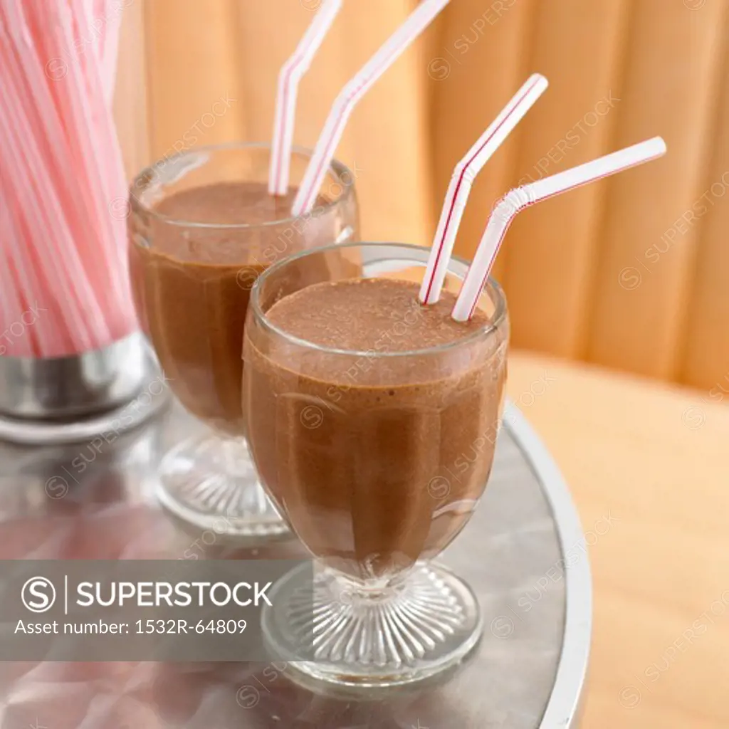 Two chocolate milkshakes with straws