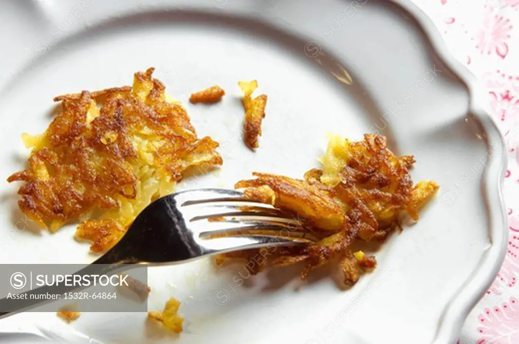 A potato rösti (hash brown) on a plate with a fork