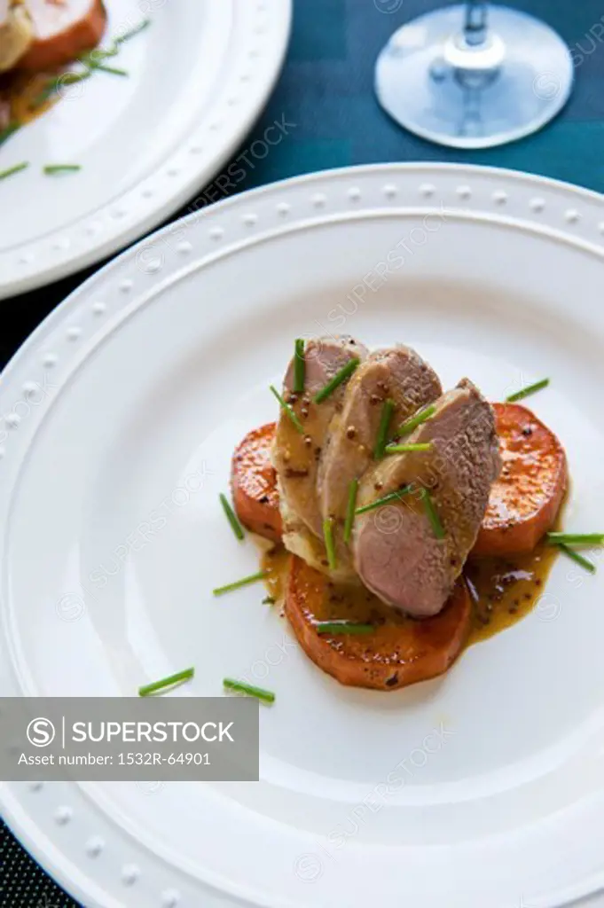 Three Pork Tenderloin Slices with Parsnip Puree on Roasted Sweet Potato Slices with a Mustard Maple Rum Sauce and Chives
