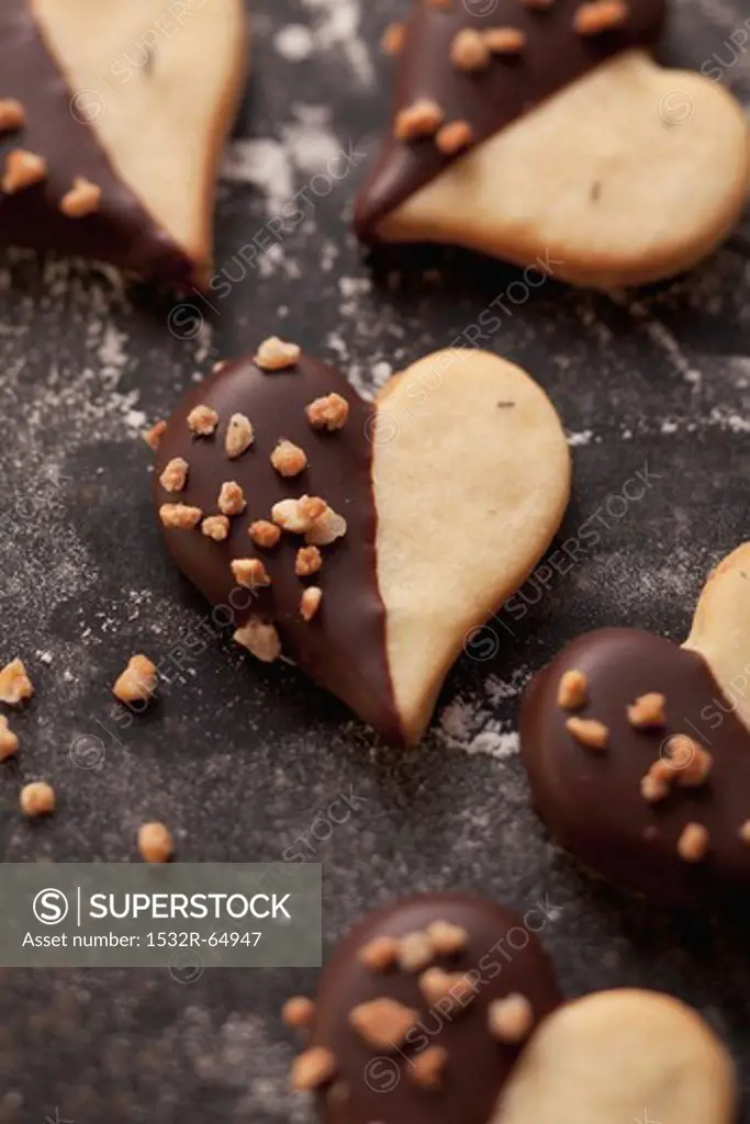 Heart-shaped biscuits decorated with chocolate icing and chopped nuts