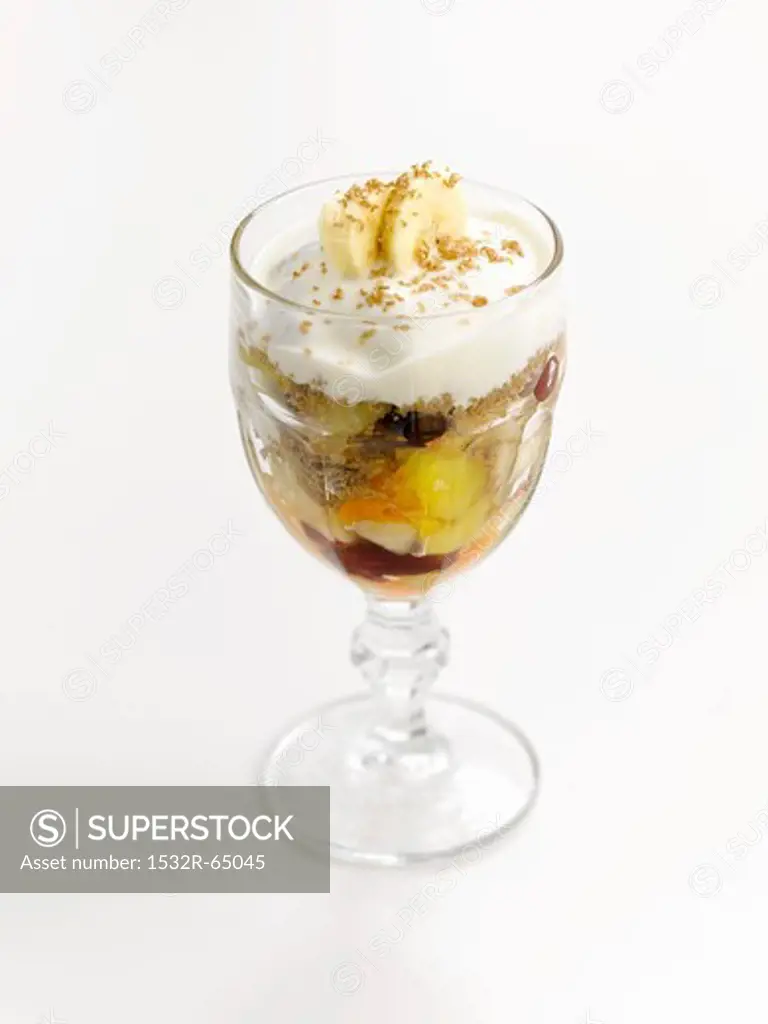 An ice cream sundae with fruit salad and cream