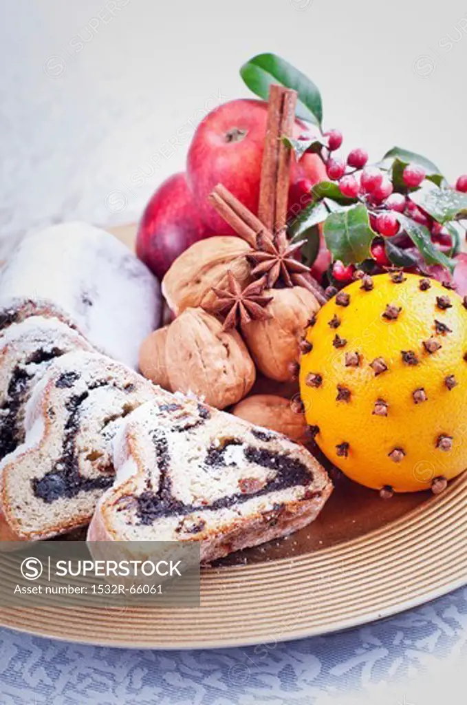 Polish poppyseed stollen, nuts, apples and an orange pierced with cloves on a plate