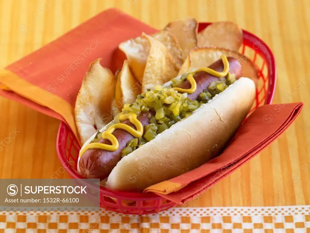 Hot Dog Topped with Relish and Mustard with Chips in a Plastic Take-Out Basket