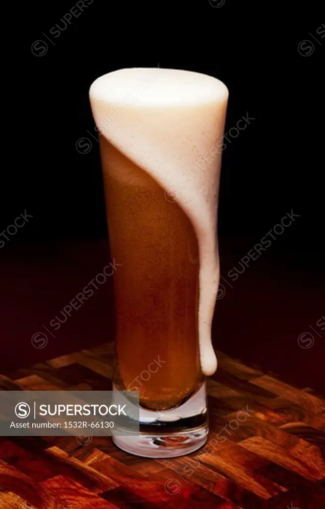 Glass Mug of Beer with Foam Spilling Over