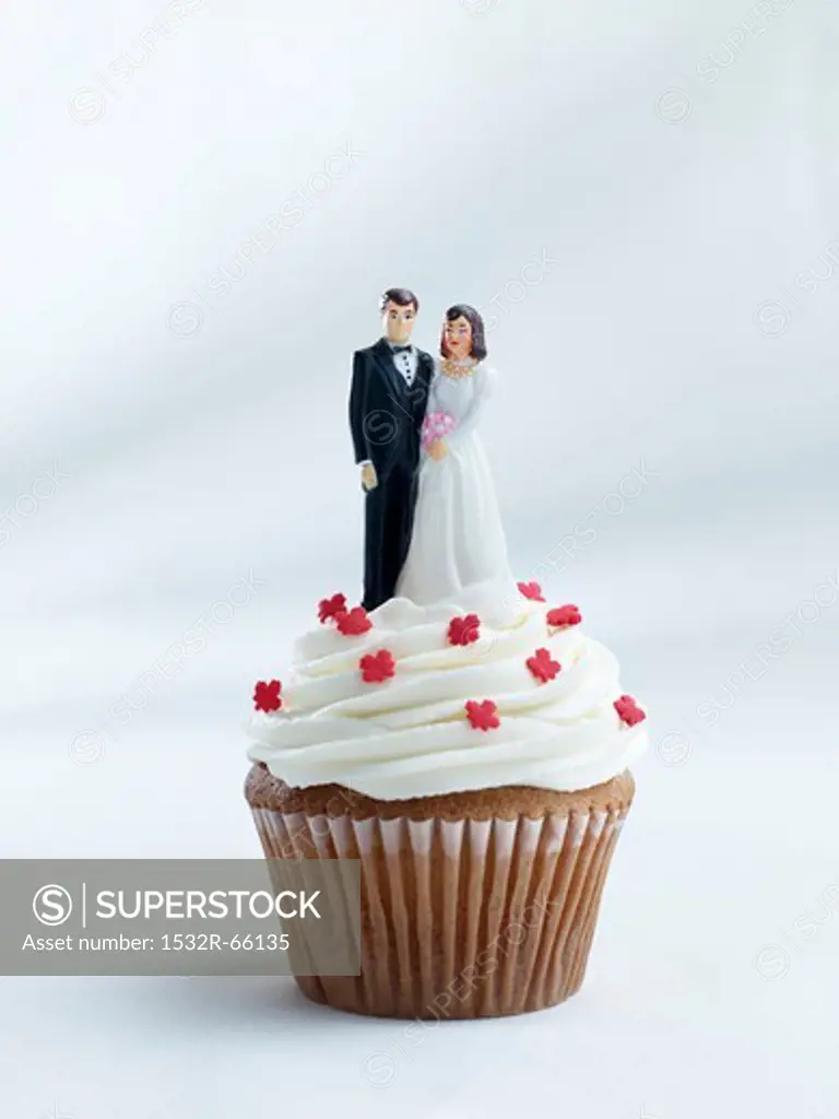 A cupcake topped with a bride and groom