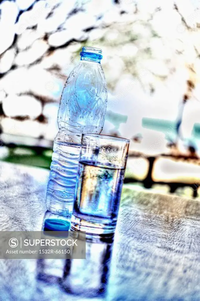 A bottle of water and a glass of water on a table