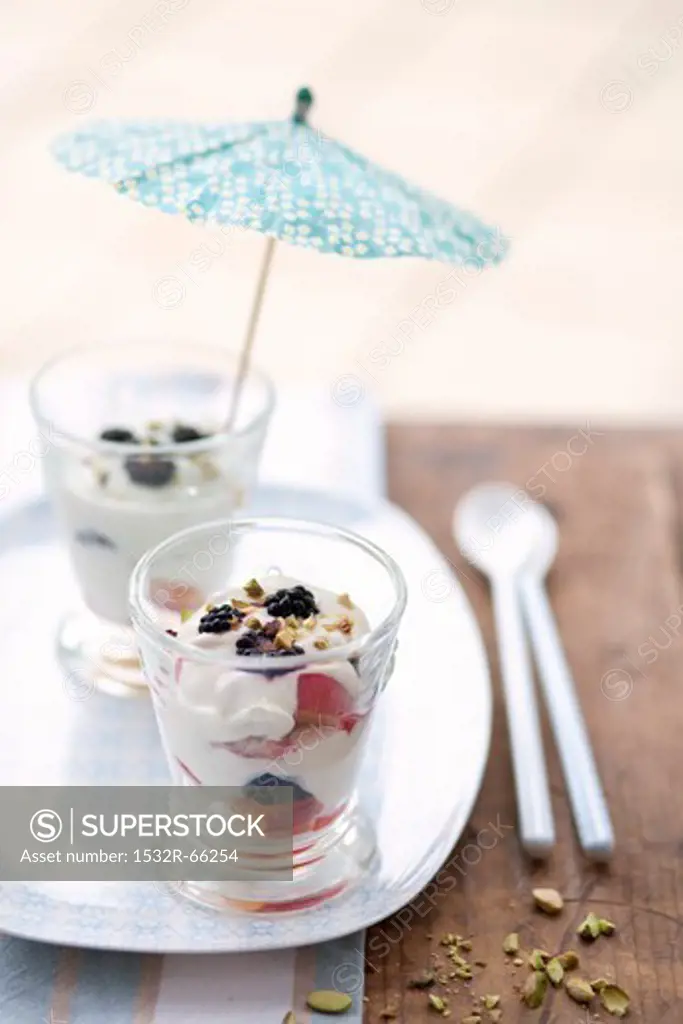 Two Glasses of Yogurt and Fruit; One with a Cocktail Umbrella