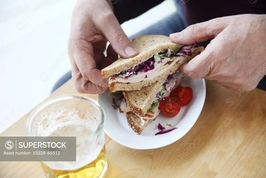 Man Holding Half of a Turkey Sandwich with Coleslaw