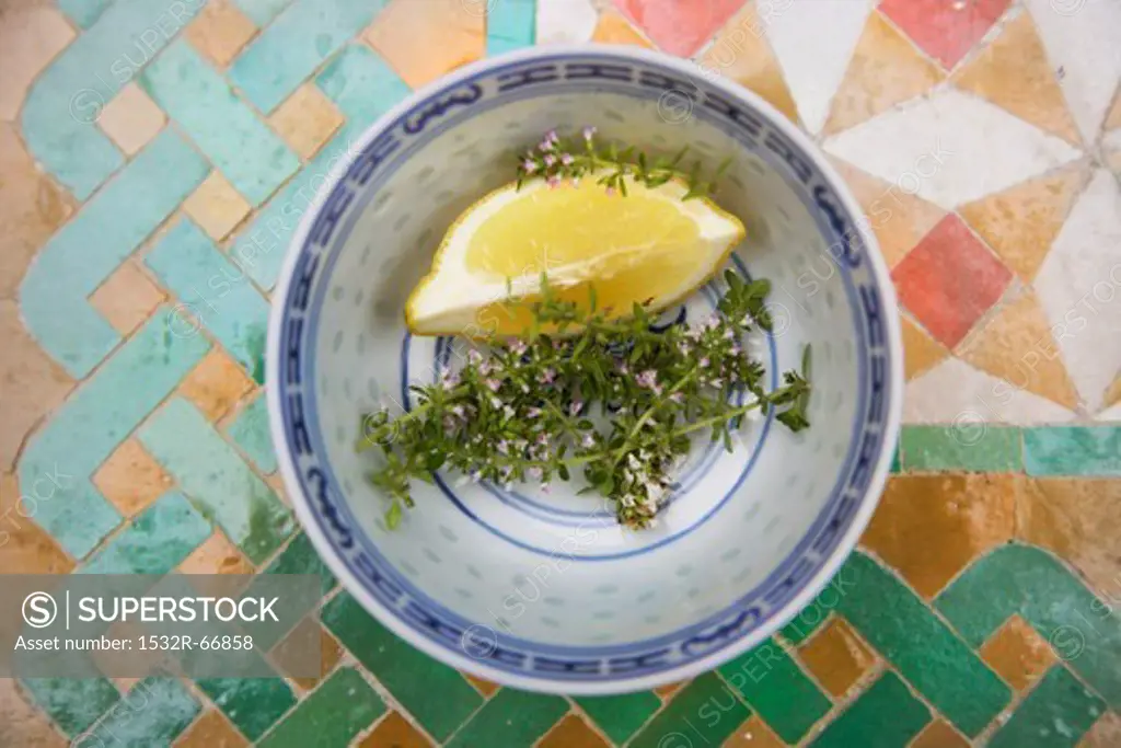 Thyme and a lemon wedge in a bowl
