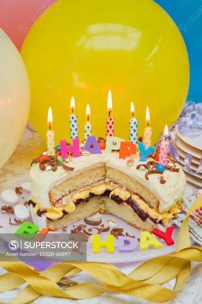 Sponge layer cake with candles for a birthday, and balloons