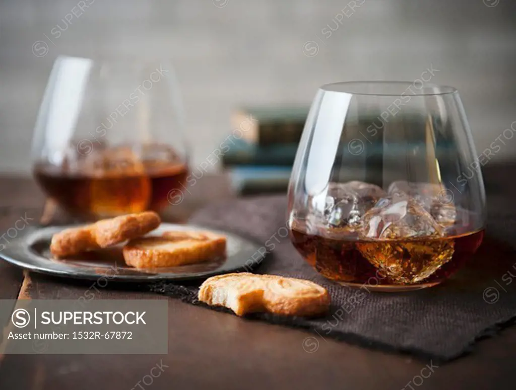 Two Stemless Glasses of Whisky on the Rocks with Cookies