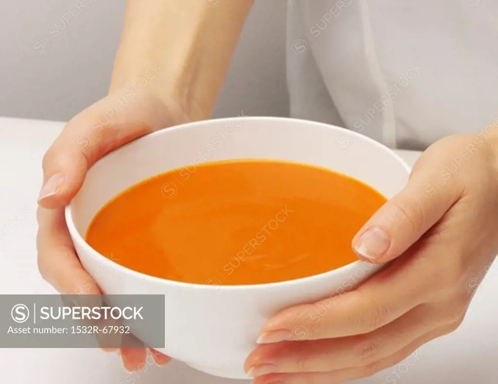 A woman's hands holding a bowl of cream of tomato soup