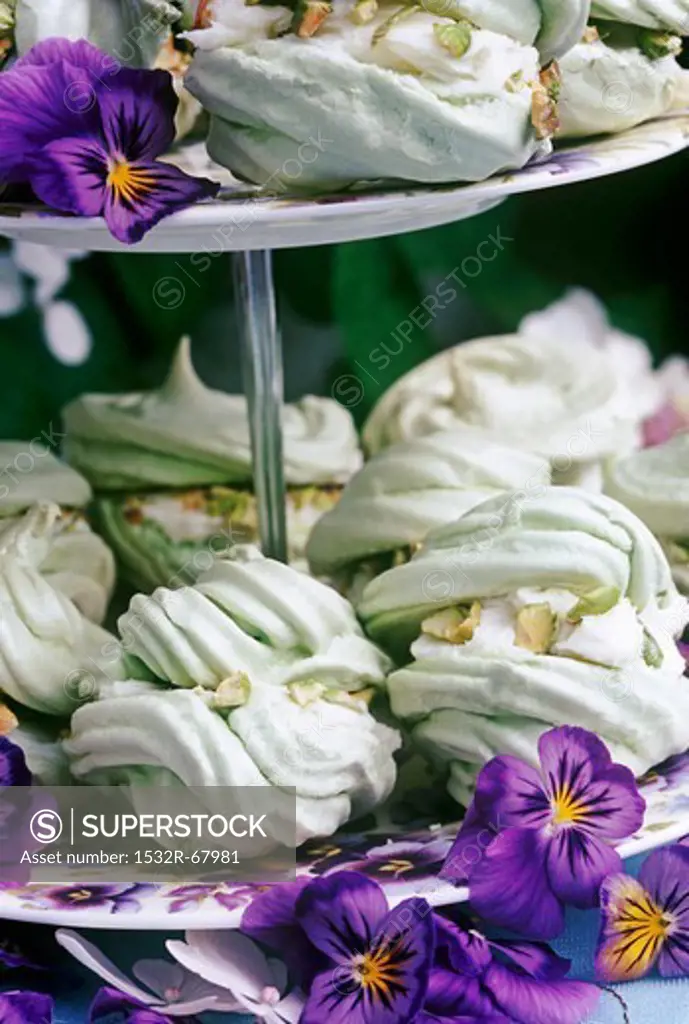 pistacio meringues on a cake stand with pansy flowers