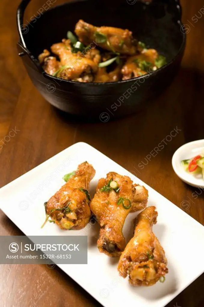Asian Style Chicken Drumettes on a Platter; Chicken in Bowl in Background