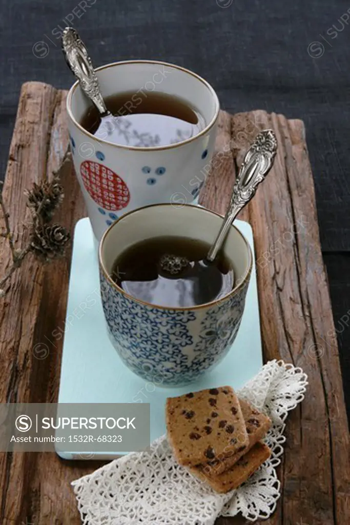Chinese tea mugs, shortcakes and a doily on a piece of wood