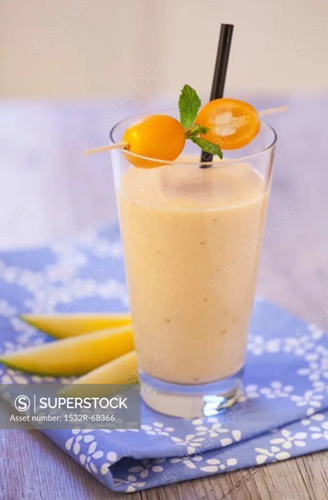 An exotic smoothie with mango and kumquats on a blue napkin on a wooden tabletop