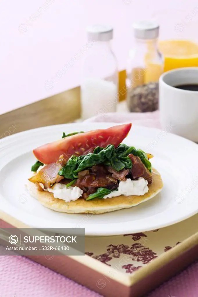 A pancake topped with ricotta, spinach and pancetta, for breakfast