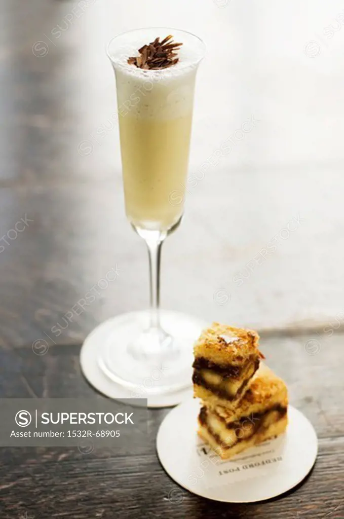 A Milkshake in a Champagne Flute with Small Chocolate Nut Sandwich Squares
