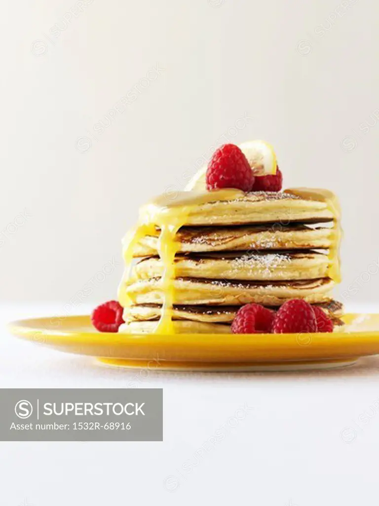 A Stack of Pancakes with Powdered Sugar, Honey and Raspberries
