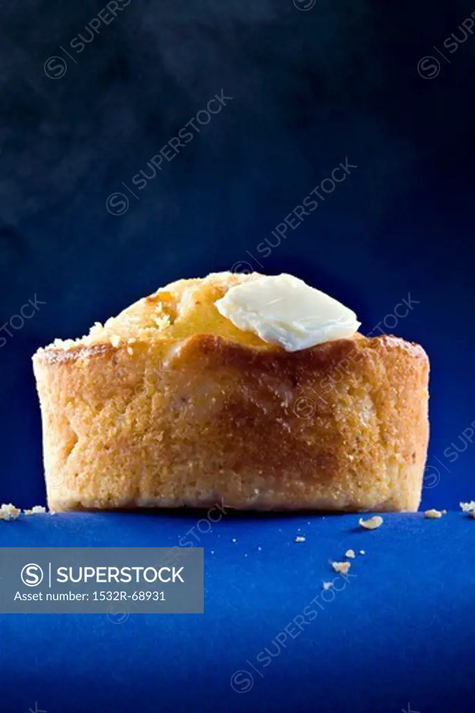 A Corn Muffin with Butter on Blue