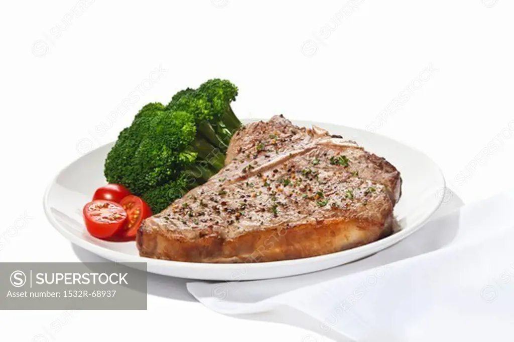 Seasoned T-Bone Steak with Cherry Tomatoes and Broccoli on a White Background