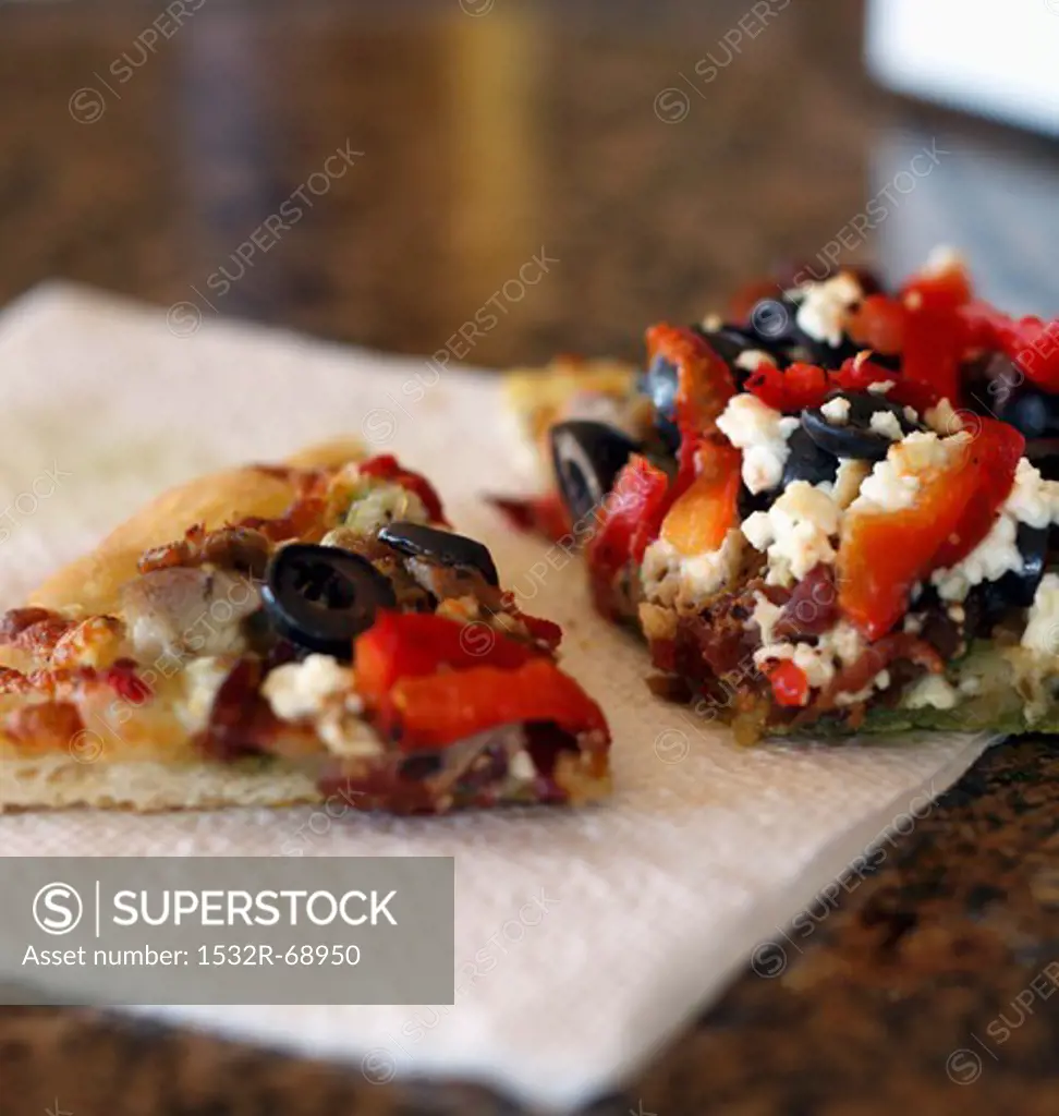 Olive, Red Pepper and Feta Pizza Slices on a Paper Napkin
