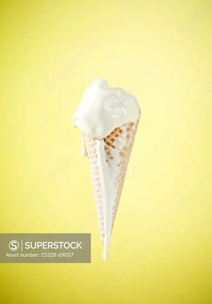 An ice cream cone with melting vanilla ice cream