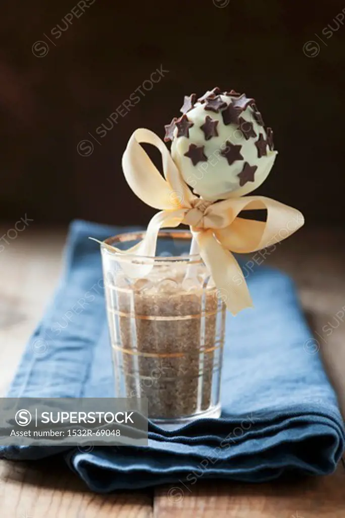 A cake pop coated in white chocolate with chocolate stars