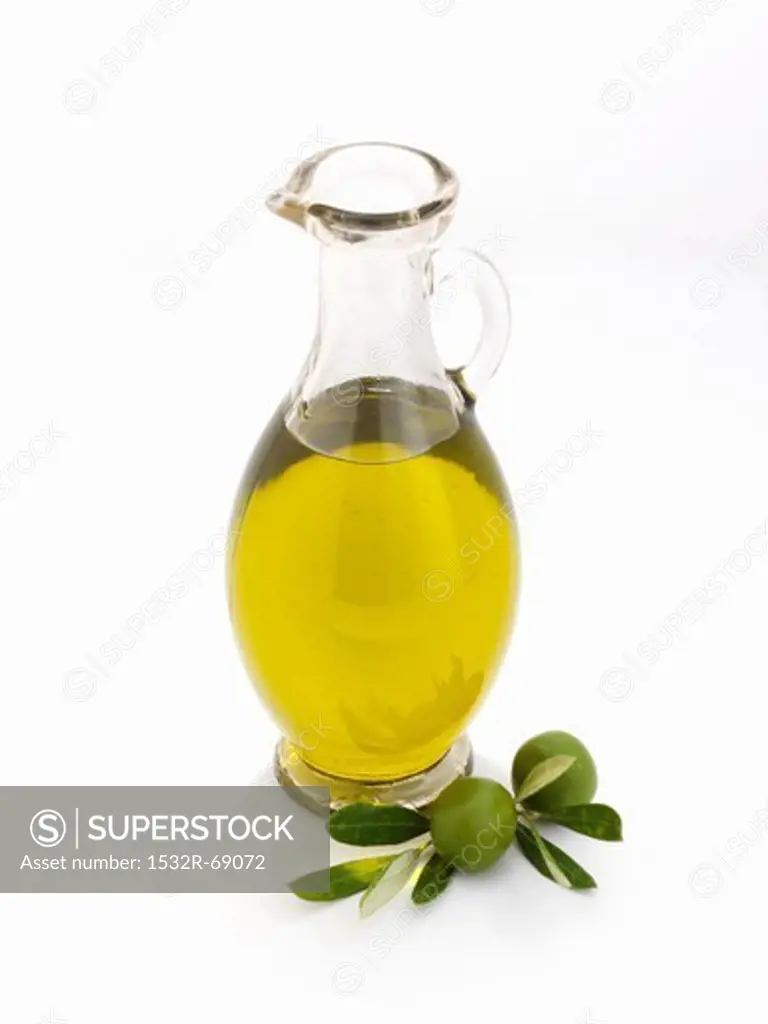 A glass carafe of olive oil against a white background