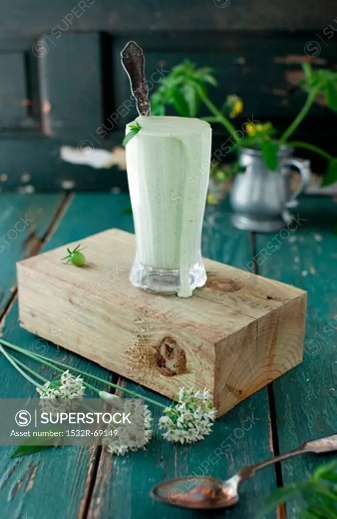 Mint Yogurt Sauce in a Tall Glass with a Spoon on a Block of Wood