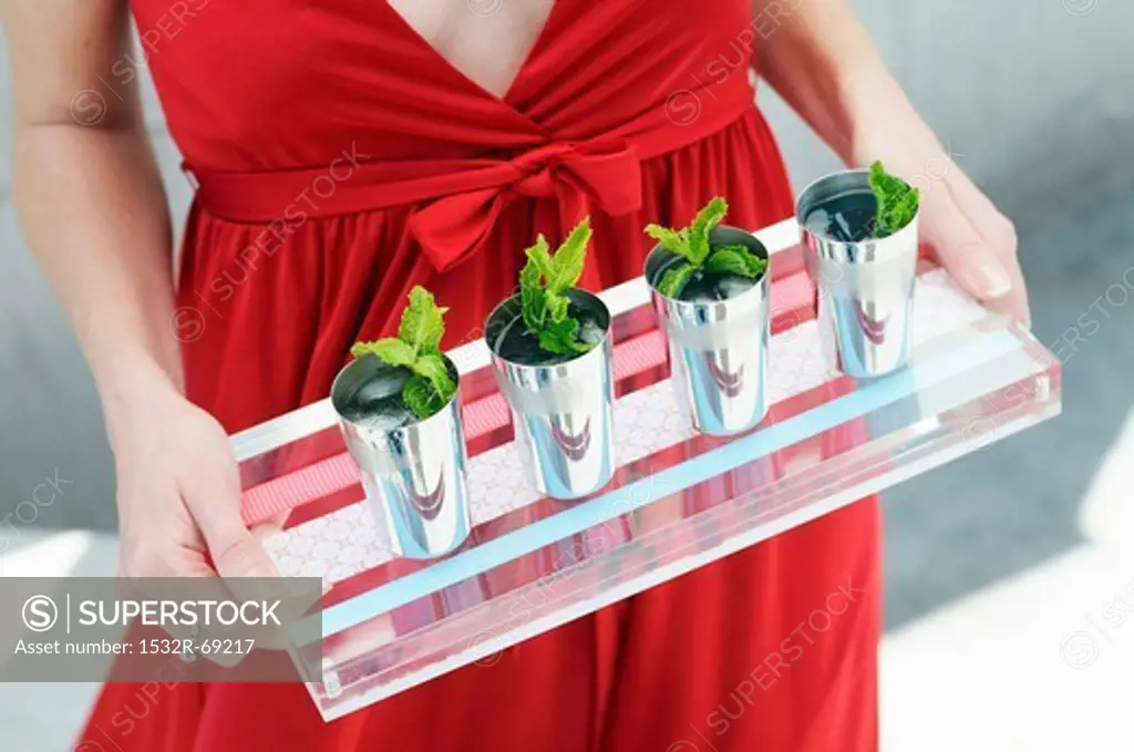 A Woman Carrying a Tray of Mint Drinks in Small Cups