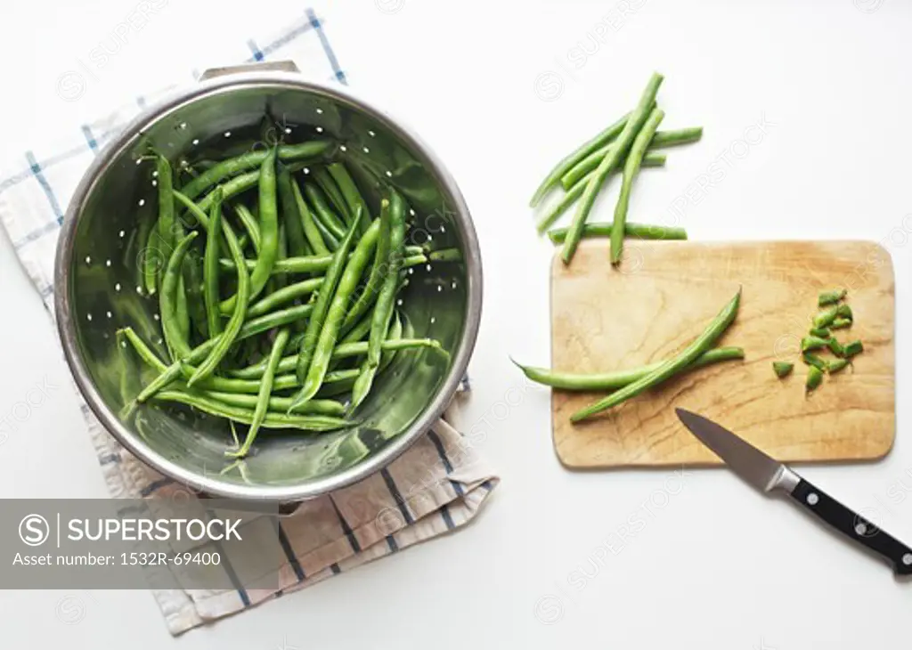 Green Beans in a Colander and on a Cutting Board with a Knife