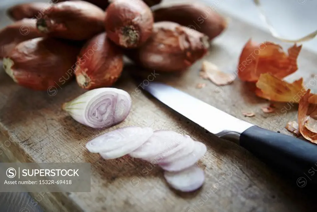 Whole and sliced shallots on a wooden board