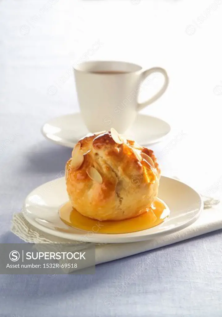 An apple in pastry in front of a cup of coffee