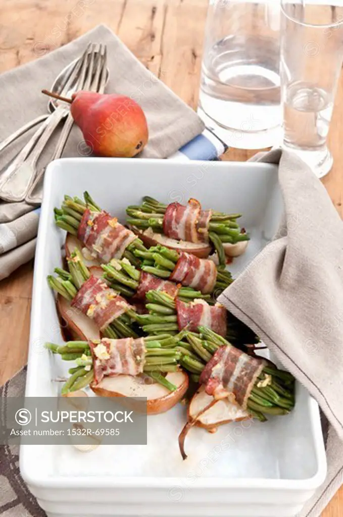 Roasted beans wrapped in bacon on top of baked pears