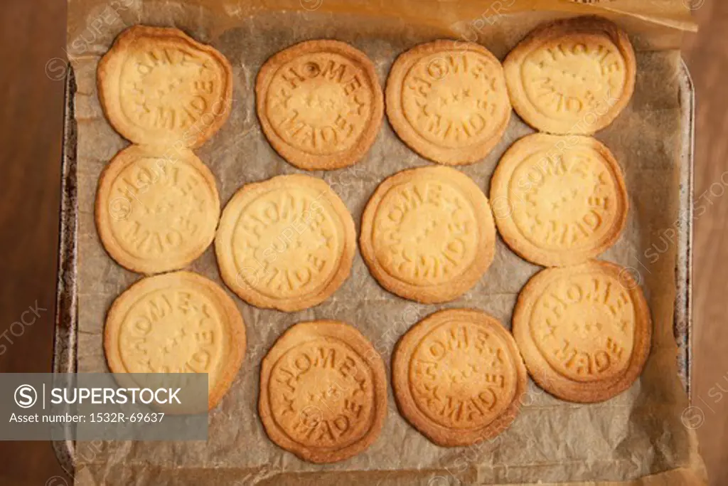 Biscuits stamped with 'home made', on a baking tray (view from above)
