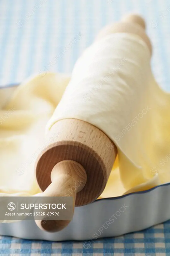 Finely rolled pastry on a rolling pin and in a tart dish