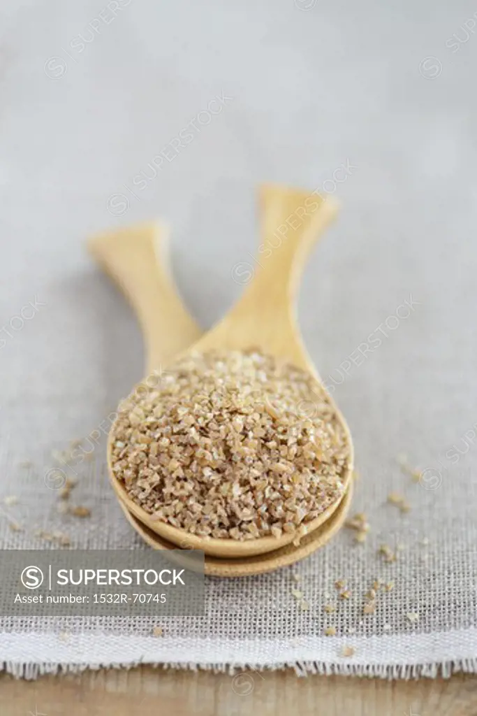 Bulgur (coarse-ground wheat) in a wooden spoon
