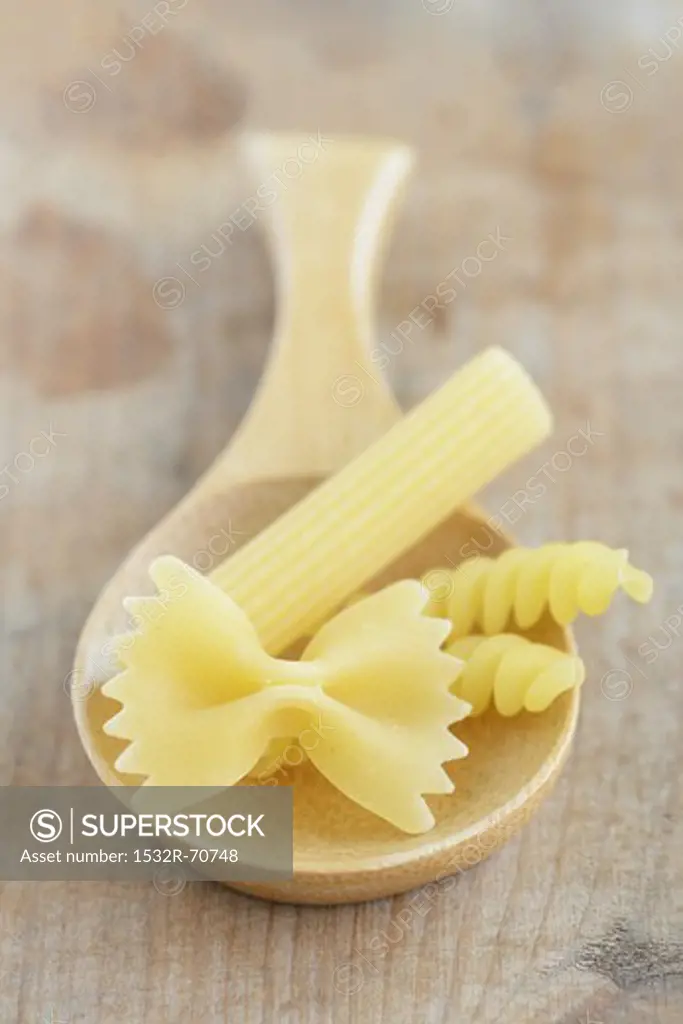Assorted types of pasta on a wooden spoon