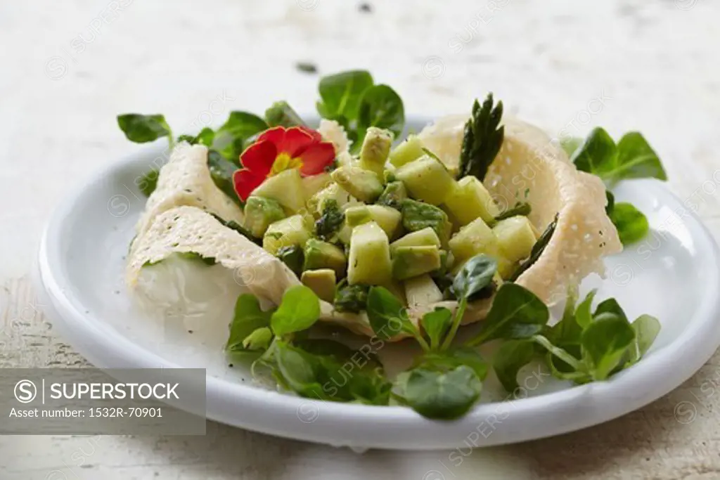 A parmesan basket filled with avocado salad and lamb's lettuce