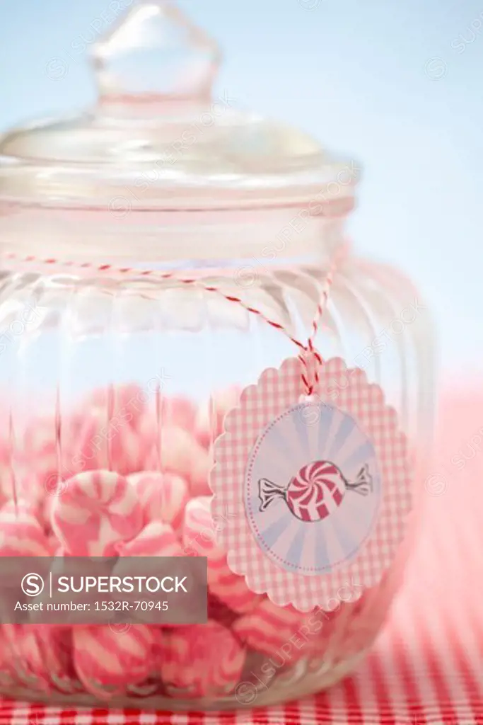 A jar of pink and white striped sweets