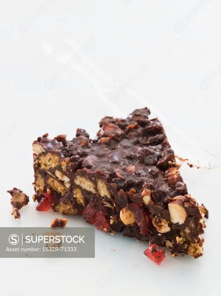 A slice of chocolate biscuit cake with glacé cherries and nuts