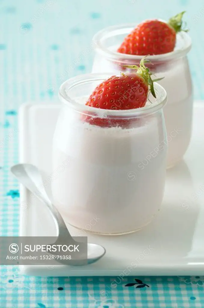 Natural yoghurt in glass pots, garnished with fresh strawberries