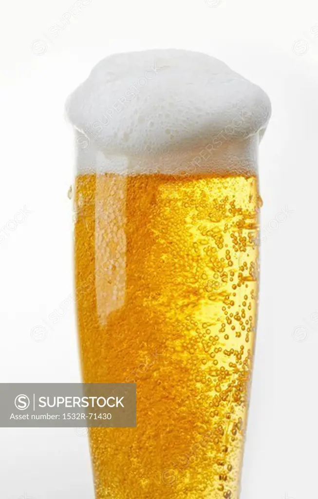 A glass of light beer with beer foam