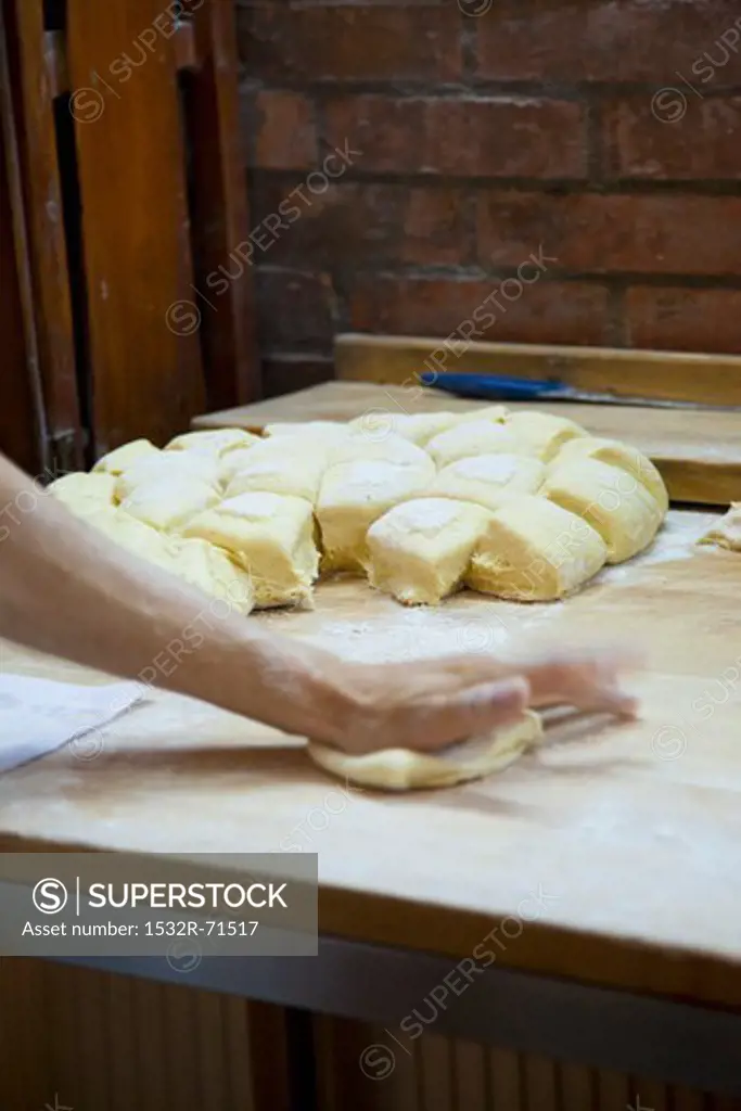 Hands shaping bread rolls in a bakery