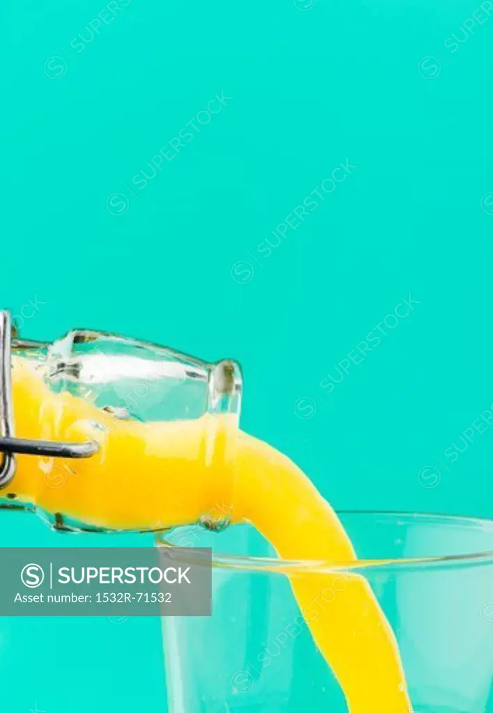 Orange juice with bits of pulp being poured from a bottle into a glass