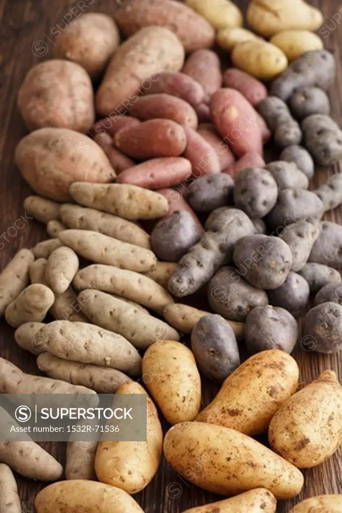 Assorted types of potatoes on a wooden surface