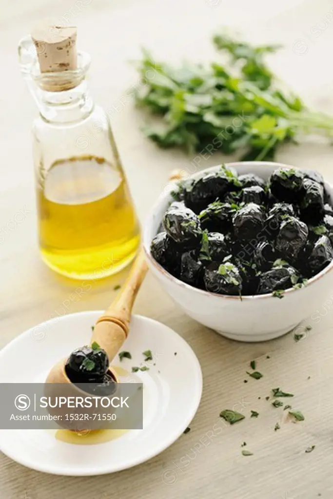 Black olives in a bowl, with parsley and olive oil