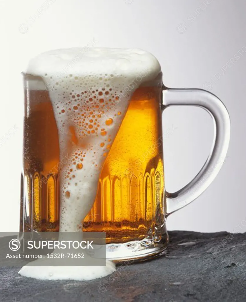 Glass of Light Beer with Foam Spilling Over