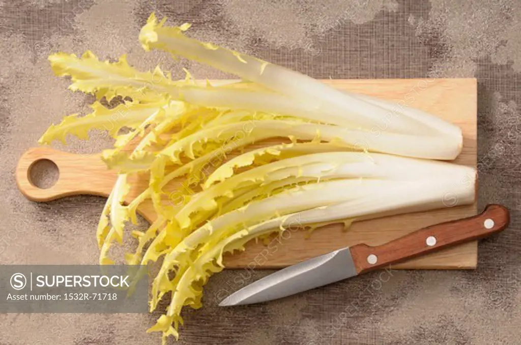 Dandelion leaves on a chopping board with a knife
